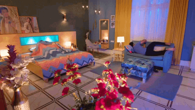 a man laying on a couch in a bedroom with flowers in the foreground