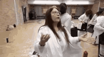 a woman is standing in a room with her arms outstretched and a group of people standing around her .