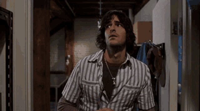 a man in a striped shirt is standing in a room