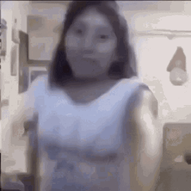 a blurry picture of a girl in a white shirt standing in front of a wall .