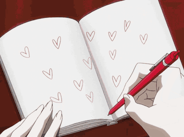 a person is writing in a notebook with red hearts drawn on it
