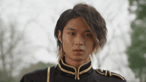 a young man with long hair is wearing a black uniform