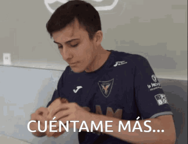 a man in a blue shirt is eating a sandwich with the words cuentame mas written below him