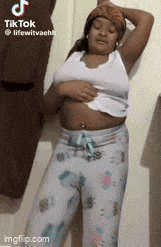 a woman is standing in front of a wall holding her belly .