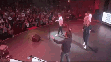 a group of people are standing on a stage in front of a microphone .