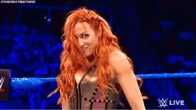 a woman with red hair is standing in a wrestling ring on a wrestling show .