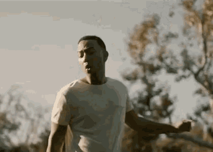 a man in a white t-shirt is running through a field .