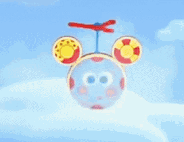 a cartoon character with a face and ears is flying in the sky .