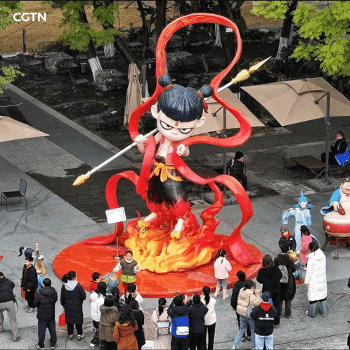 a group of people are gathered around a statue that says cgtn on the top