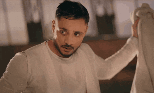 a man with a beard is wearing a white shirt that says ' calvin klein ' on it