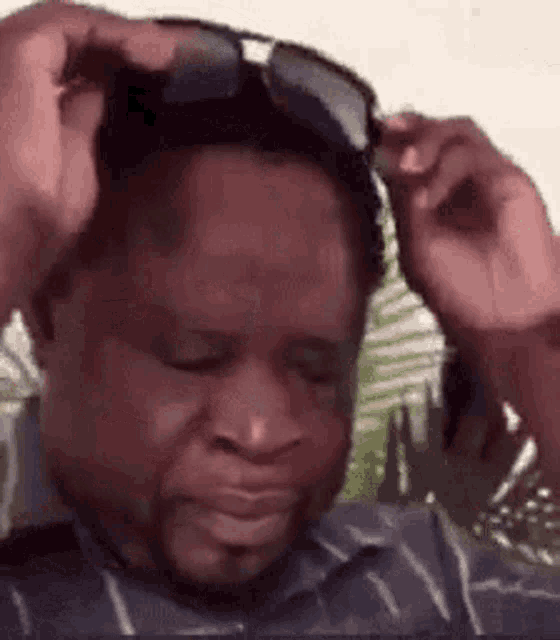 a man wearing sunglasses is holding his head and making a funny face .