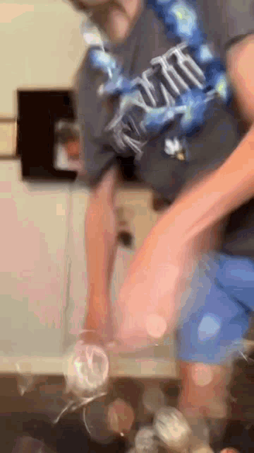 a man in a t-shirt is throwing a bottle of soda on the floor .