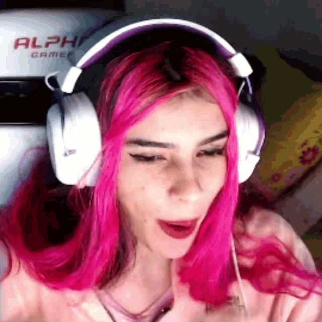 a woman with pink hair is wearing headphones with the word alpha on the back