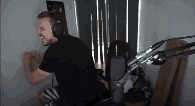 a man wearing headphones is sitting in front of a microphone and screaming .