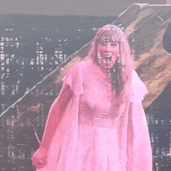 a woman in a pink dress is standing on a stage with a microphone in her hand .