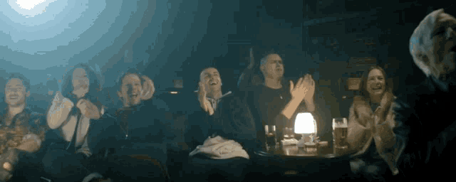 a group of people sitting at a table with their hands in the air