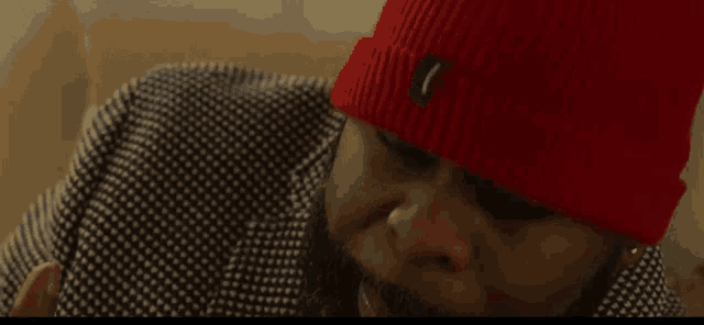 a man with a beard wears a red beanie