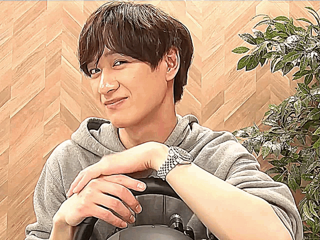 a man wearing a watch is holding a steering wheel and smiling