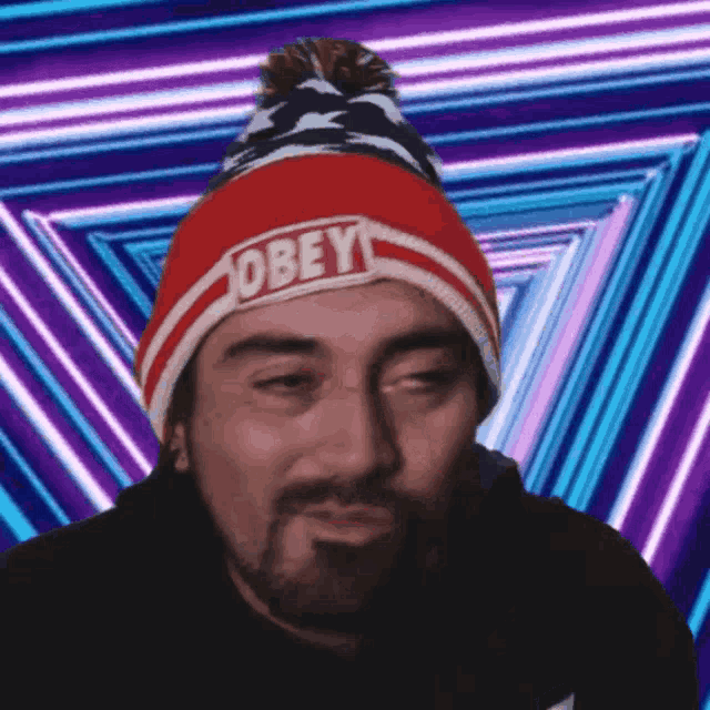 a man wearing a red white and blue obey beanie