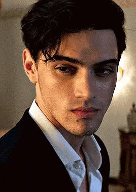 a young man in a suit and white shirt is looking at the camera with a serious look on his face .