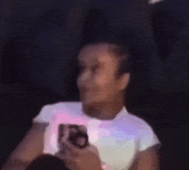 a blurry picture of a person laying on a couch holding a phone .