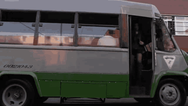 a green and gray bus has the number 002043 on the side