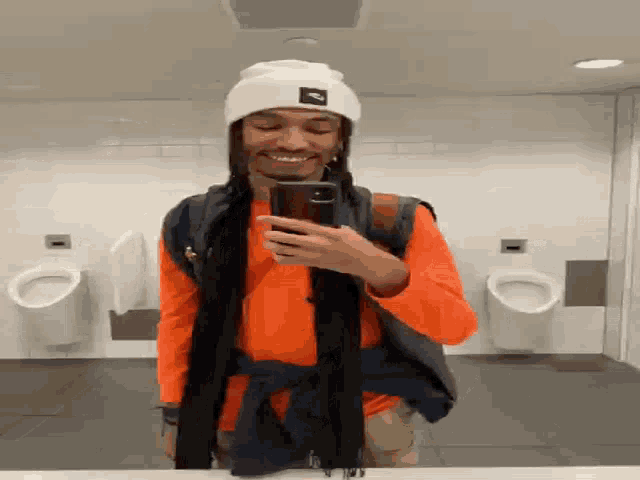 a man taking a selfie in a public bathroom