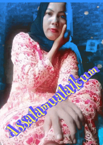 a woman wearing a hijab sits in front of a sign that says assalaamualaikum