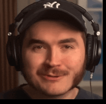 a man wearing headphones and a ny hat smiles