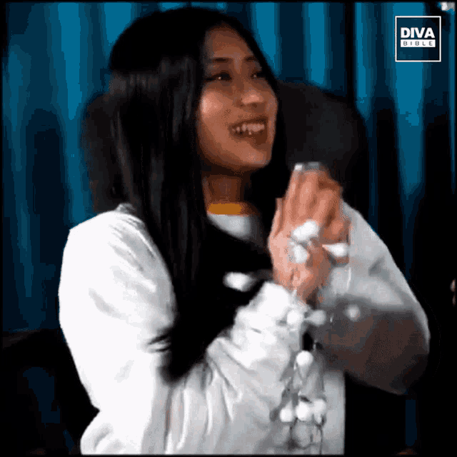 a woman with long hair is smiling in front of a diva girls logo