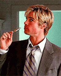 a man in a suit and tie is holding a pen to his forehead