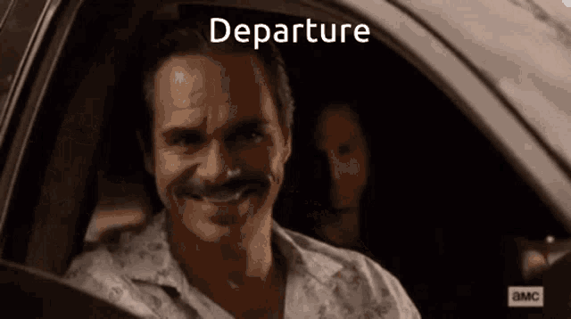 a man with a mustache is smiling in a car with the word departure written above him