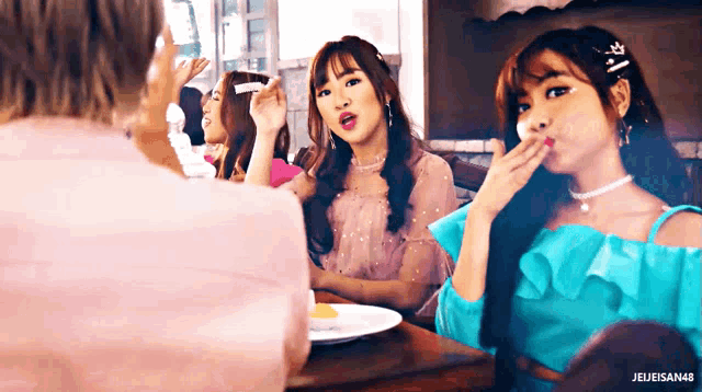 a group of girls are sitting at a table with a plate of food in front of them and the name jejeisan48 is visible