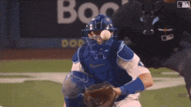 a baseball catcher catches a ball in front of an ad for boo