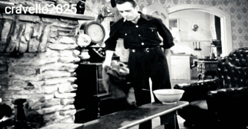 a black and white photo of a man standing in front of a fireplace with the name cravello written on the bottom