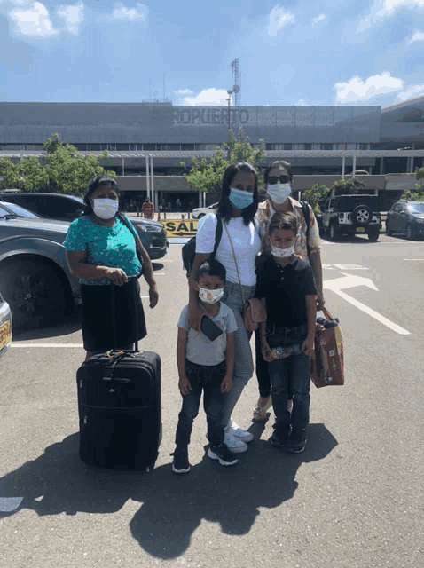 a group of people wearing face masks in front of a building that says aeroporto