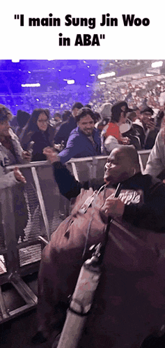 a man is sitting in a crowd of people and says " i main sung jin woo in aba " on the bottom