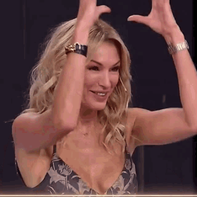 a woman in a bikini top is raising her hands in the air and smiling .