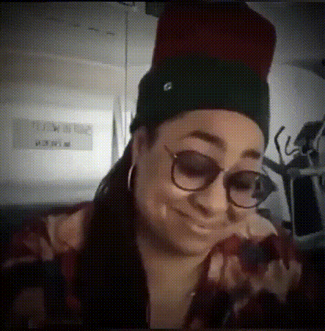 a woman wearing glasses and a beanie looks at her phone