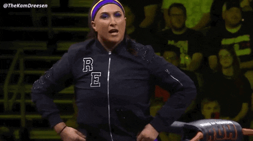 a woman wearing a headband and a jacket is standing in front of a crowd .