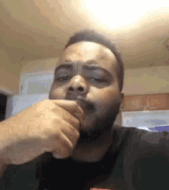 a man with a beard is covering his mouth with his hand while looking at the camera .