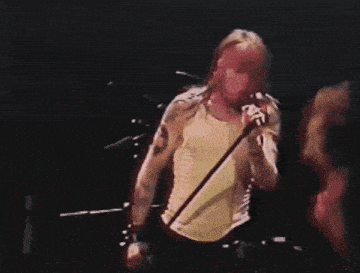 a man with a tattoo on his arm singing into a microphone on a stage