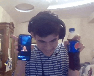 a man holding a bottle of pepsi and a cell phone