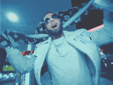 a man wearing sunglasses and a louis vuitton scarf has his arms outstretched in the air