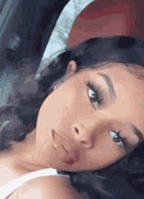 a woman is laying in the back seat of a car taking a selfie .