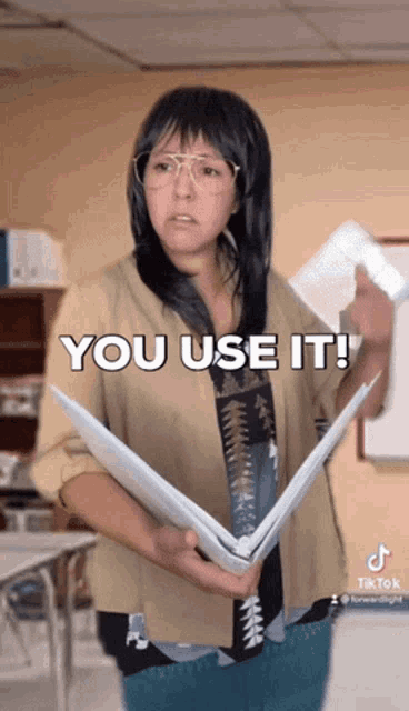 a woman holding a binder with the words you use it on it