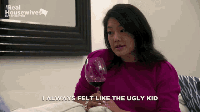 a woman holding a glass of wine with the words i always felt like the ugly kid below her