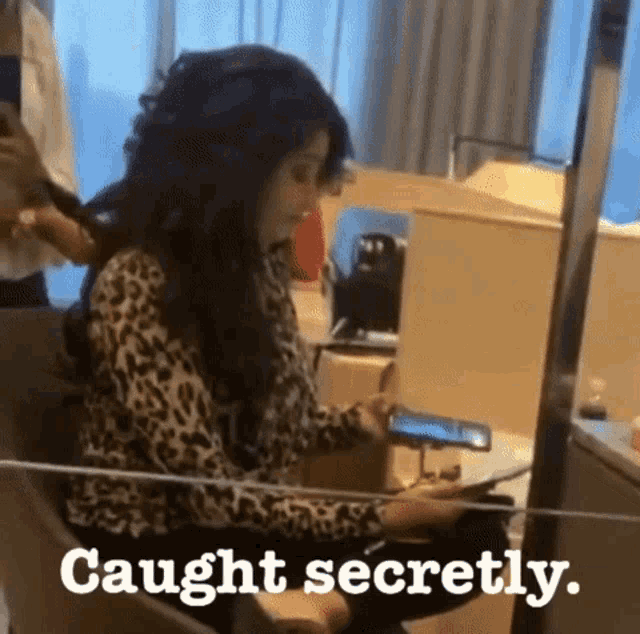 a woman is sitting in front of a mirror looking at her phone and the words caught secretly are on the bottom