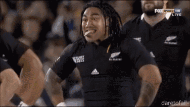 a man in a black all blacks jersey is making a funny face