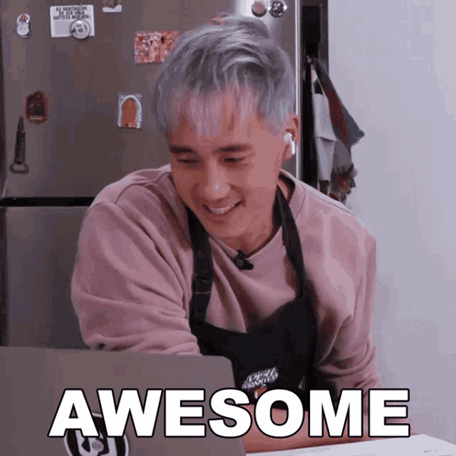 a man wearing an apron is smiling and looking at a laptop with the words awesome written on the screen